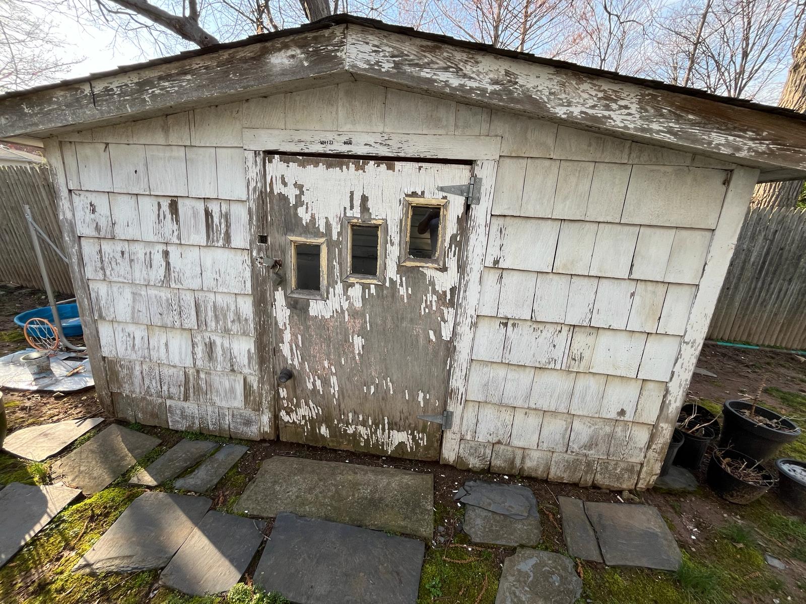 Weathered backyard shed with peeling paint restored with a clean gray exterior finish — before